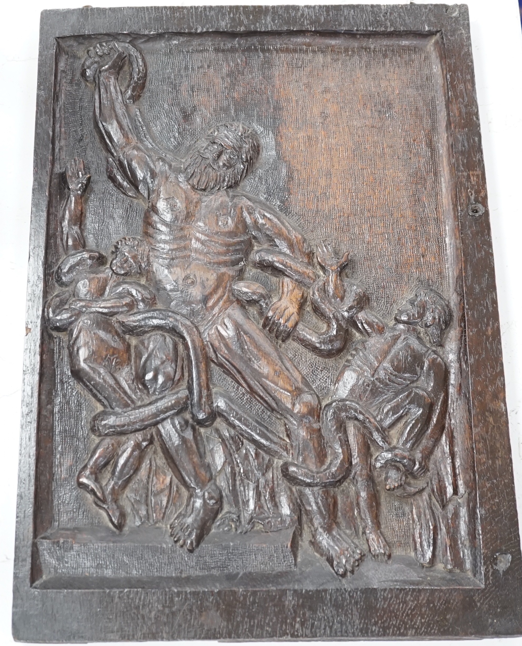 A carved oak figural panel depicting Laocoön and his son is fighting serpents, 46 x 32cm